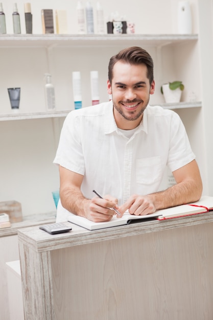 Trabalhador de salão sorridente com livro de ações no trabalho