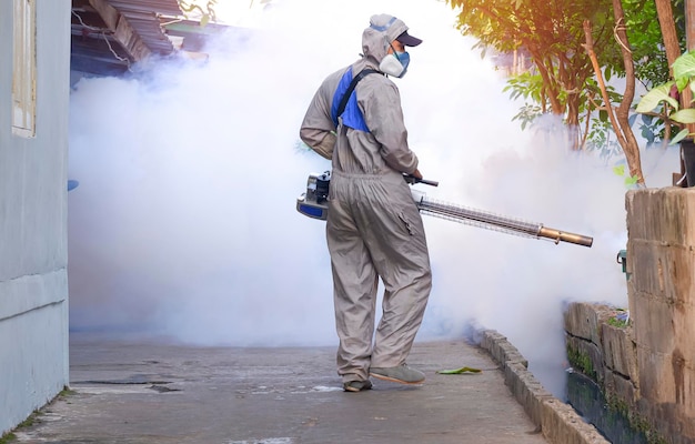 Trabalhador de saúde ao ar livre pulverizando produtos químicos para eliminar mosquitos e prevenir a dengue na favela