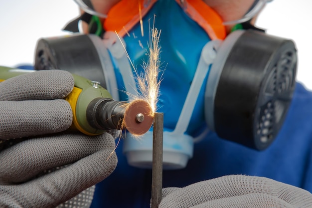 Trabalhador de serralheiro masculino processa metal com corte de broca de gravação O trabalho da ferramenta elétrica de gravação dremel Indústria de processamento de metal industrial