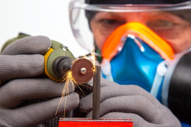 Trabalhador de serralheiro masculino processa metal com corte de broca de gravação O trabalho da ferramenta elétrica de gravação dremel Indústria de processamento de metal industrial