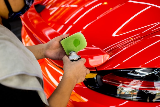 Trabalhador de serviço de carro aplicando revestimento nano em um detalhe do carro