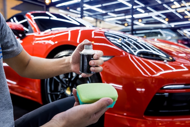 Trabalhador de serviço de carro aplicando revestimento nano em um detalhe do carro