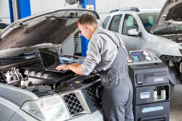 Trabalhador de serviço de carro realiza diagnósticos e reparos de carro na sala.