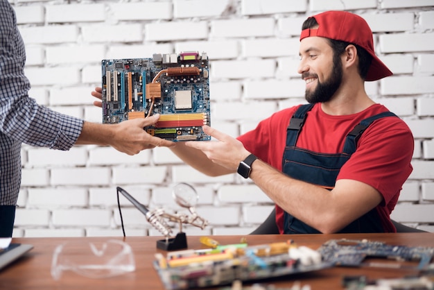 Trabalhador de serviço de computador recebe uma placa-mãe.