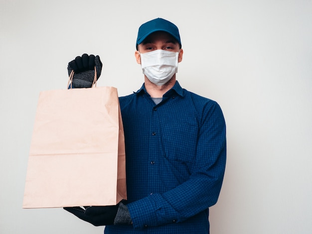 Foto trabalhador de serviço de entrega de alimentos vestindo camisa azul, acampamento, máscara e luvas na pandemia de covid-19.