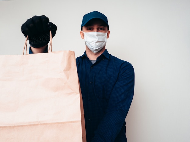Trabalhador de serviço de entrega de alimentos vestindo camisa azul, acampamento, máscara e luvas na pandemia de COVID-19.
