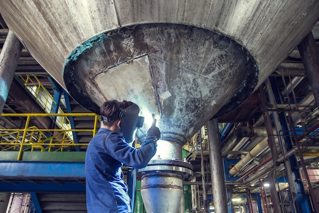 Trabalhador de soldagem repara tanque inferior de silo de aço inoxidável usando soldador tig