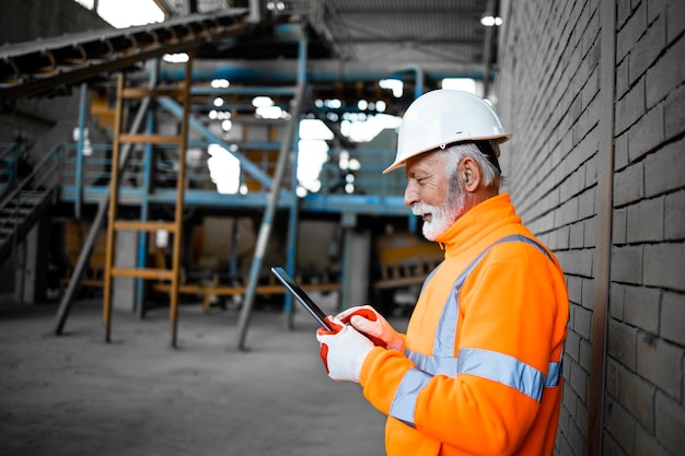 Trabalhador de supervisor industrial verificando os resultados da produção no computador tablet na fábrica.