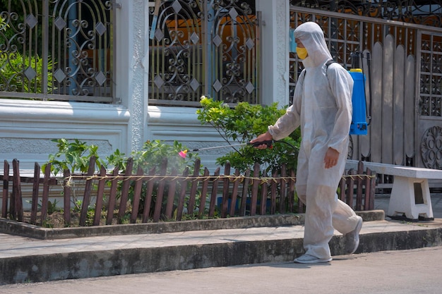 Trabalhador desinfetante pulverizando desinfetante químico em fontes comunitárias em área pública