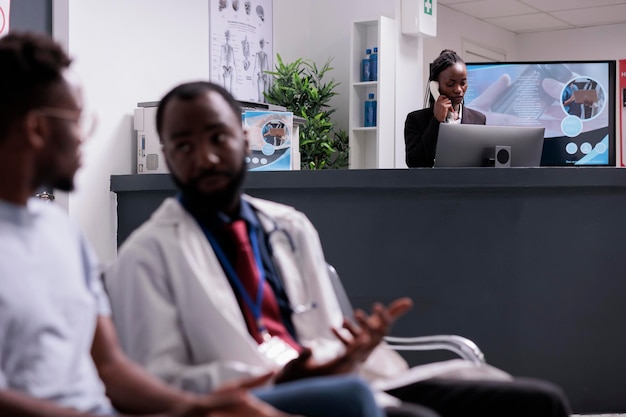 Trabalhador do hospital usando telefone fixo para marcar consultas com especialista no centro de saúde. Haivng conversação remota em linha telefônica com pacientes no balcão da recepção.