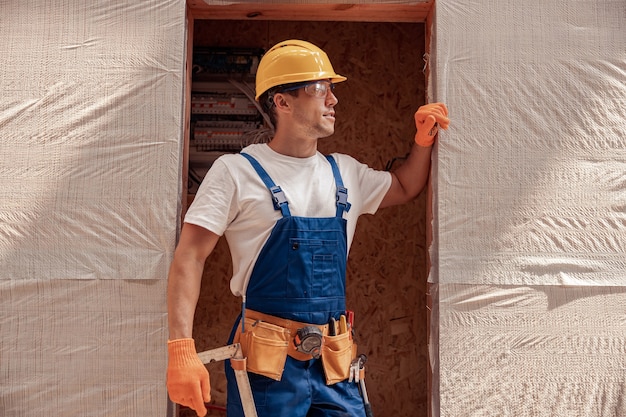 Trabalhador do sexo masculino bonito parado na porta do canteiro de obras