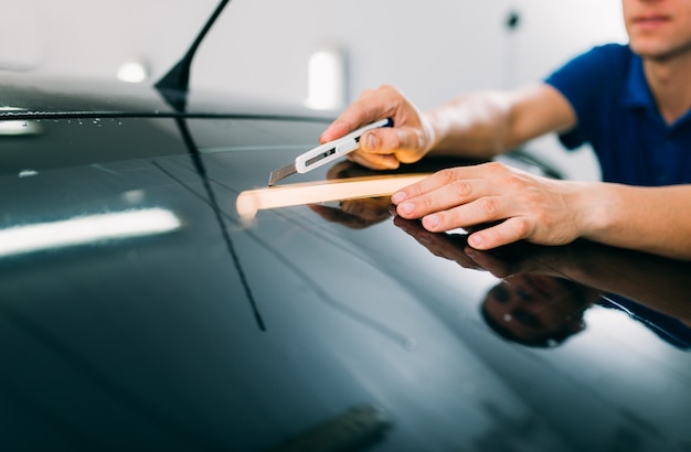 Trabalhador do sexo masculino com lâmina, processo de instalação de filme de tingimento de carro, procedimento de instalação de vidro automático matizado