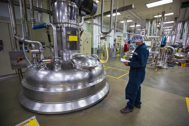 Trabalhador do sexo masculino faz a inspeção e registra o medidor de pressão do processo na instalação do tanque do equipamento nos tanques verticais da fábrica de aço inoxidável