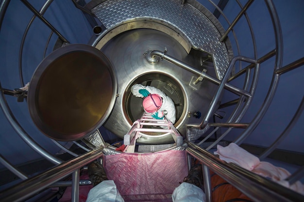 Trabalhador do sexo masculino vista de cima subindo as escadas para a área de produtos químicos do tanque segurança em espaço confinado