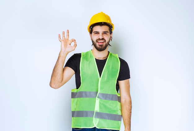 Trabalhador em capacete amarelo, mostrando sinal de satisfação.