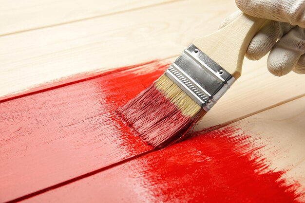 Trabalhador em luvas pintando superfície de madeira com corante vermelho closeup Espaço para texto