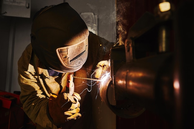 Foto trabalhador em máscara de segurança solda metal em empresas industriais