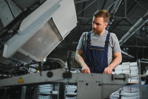 Trabalhador em roupas de proteção na fábrica usando máquina