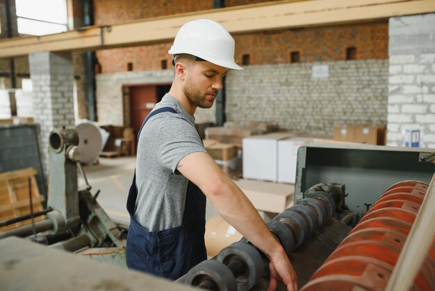 Trabalhador em roupas de proteção na fábrica usando máquina