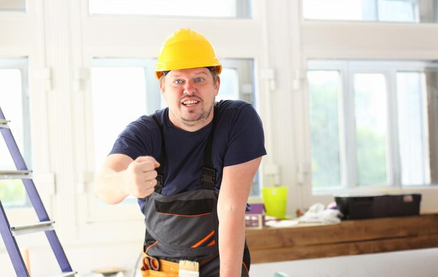 Trabalhador engraçado sorridente em capacete amarelo posando