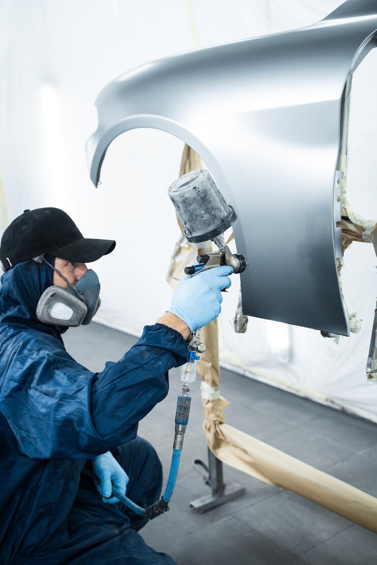 Foto trabalhador está pintando carro em cor escura com pistola de spray hvlp mecânico de automóveis está mudando a cor do veículo usando esponja e pulverizador de pintura