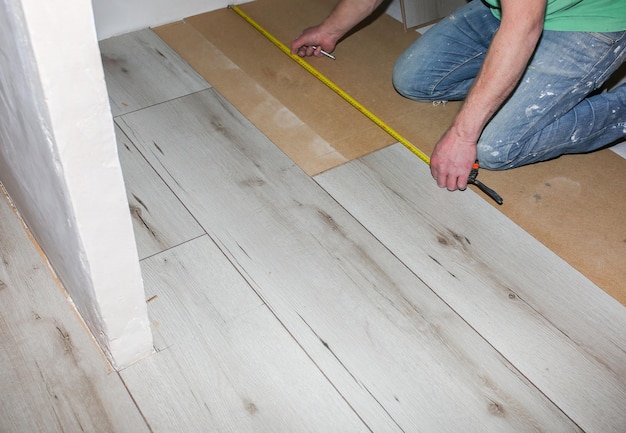 Trabalhador fazendo piso laminado em apartamento Renovação de reparo de manutenção Pranchas de parquet de madeira dentro de casa