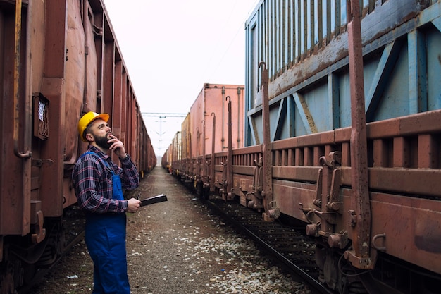 Trabalhador ferroviário inspecionando contêineres de transporte de carga.
