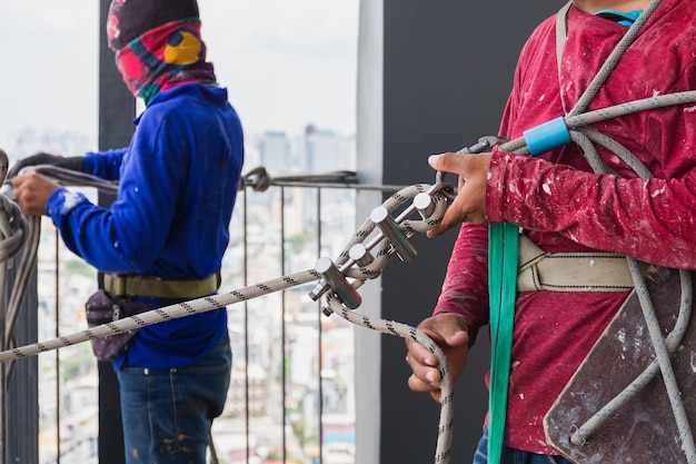 Trabalhador industrial ajustando equipamento de escalada preparando corda de segurança