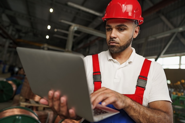 Trabalhador industrial com laptop trabalhando em uma planta de produção de cabos