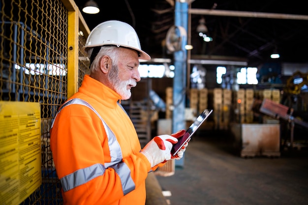 Trabalhador industrial ou supervisor controlando o processo de produção via computador tablet na fábrica.