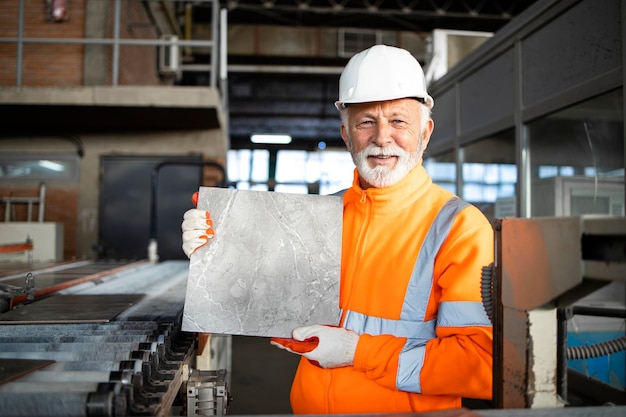 Trabalhador industrial profissional que trabalha na fábrica de azulejos cerâmicos e mostra o produto