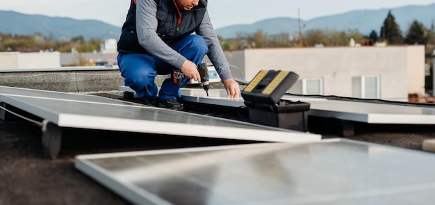 Trabalhador instalando novos painéis solares no telhado da casa da família Energia alternativa Foto da capa