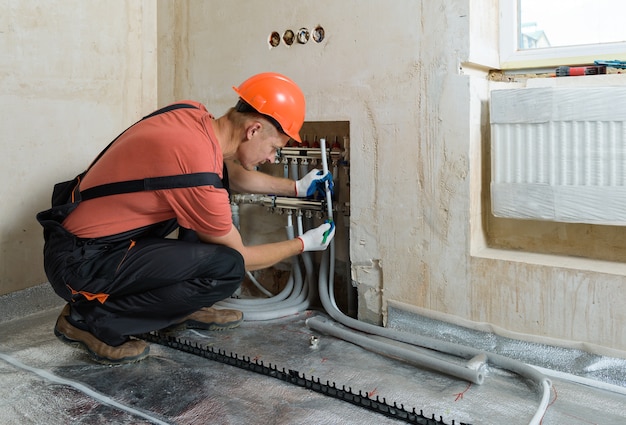 Trabalhador instalando um cano para o piso quente do apartamento