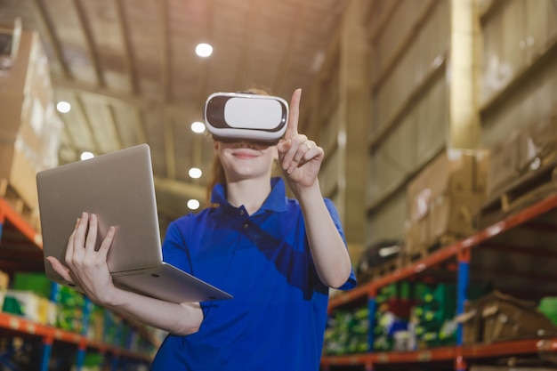 Trabalhador inteligente usando dispositivo VR digital de tecnologia avançada moderna para controlar, operar e gerenciar o armazém de estoque de produtos da indústria