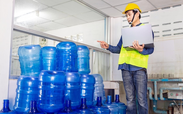 Trabalhador jovem e inspetor de qualidade em uma fábrica verificando galões de água azul antes do embarque