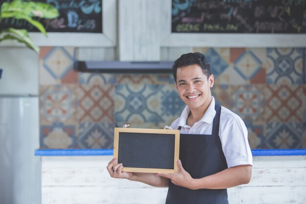 Trabalhador masculino café sorrindo e segurando lousa em branco