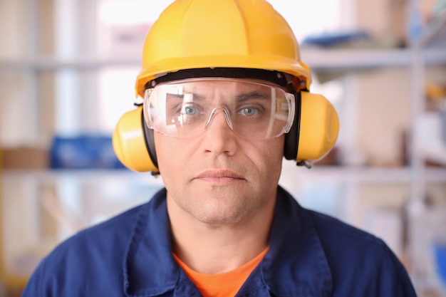 Trabalhador masculino com protetores auditivos e óculos de segurança dentro de casa