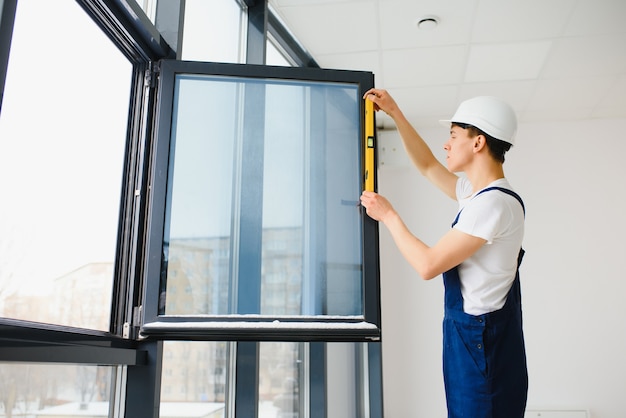 Trabalhador masculino construtor industrial na instalação de janela no canteiro de obras