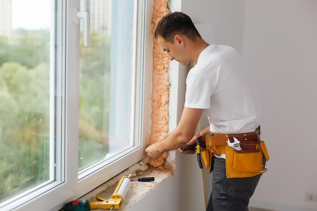 Trabalhador masculino construtor industrial na instalação de janela no canteiro de obras