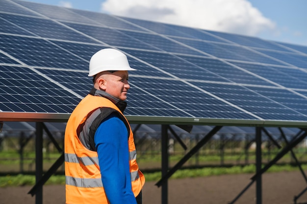 Trabalhador masculino de capacete em uma usina de energia solar no contexto dos painéis