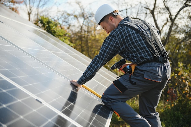 Trabalhador masculino de uniforme ao ar livre com baterias solares em dia ensolarado