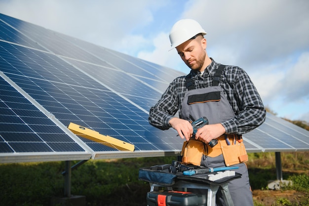 Trabalhador masculino de uniforme ao ar livre com baterias solares em dia ensolarado