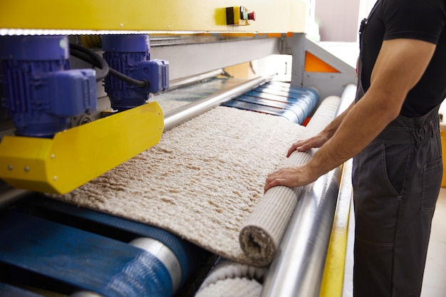 Trabalhador masculino limpando carpete em equipamento de máquina de lavar e secar roupa automática na lavanderia