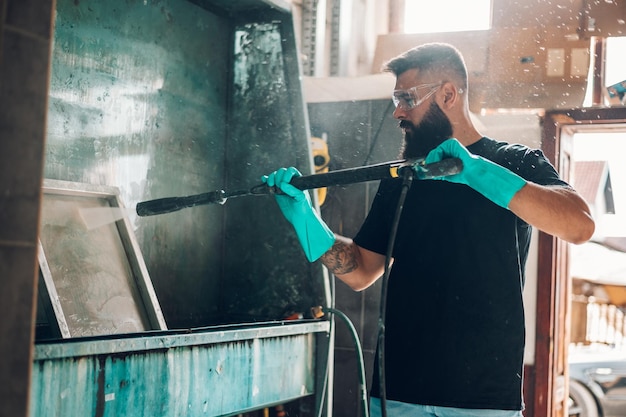 Foto trabalhador masculino, limpando o quadro de tela com água em uma oficina de impressão