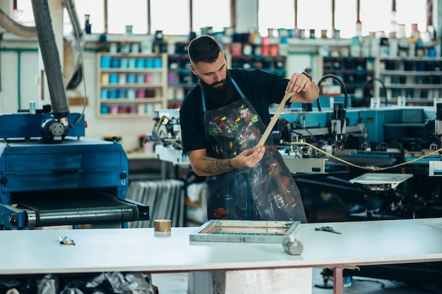 Trabalhador masculino preparando filme de serigrafia em uma oficina