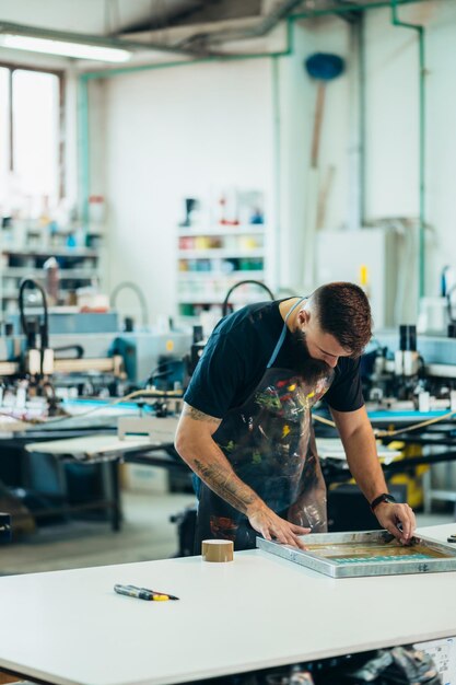 Trabalhador masculino preparando filme de serigrafia em uma oficina