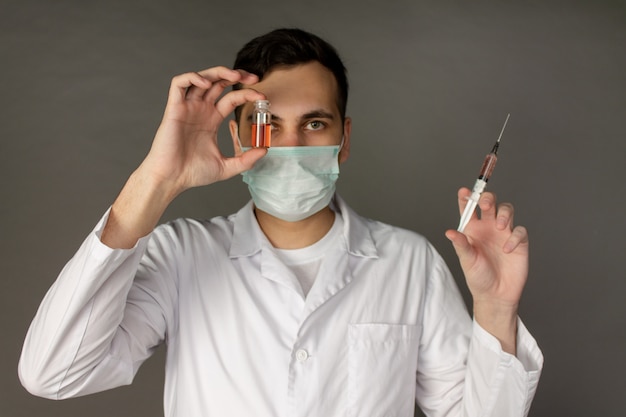 trabalhador médico detém uma vacina e usa uma máscara para proteger do coronavírus