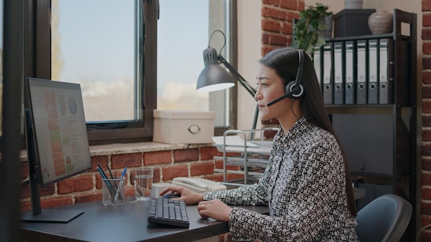 Trabalhador no atendimento ao cliente usando microfone no telefonema. Assistente de vendas conversando com clientes sobre comunicação de telemarketing com fone de ouvido, dando suporte técnico no escritório.