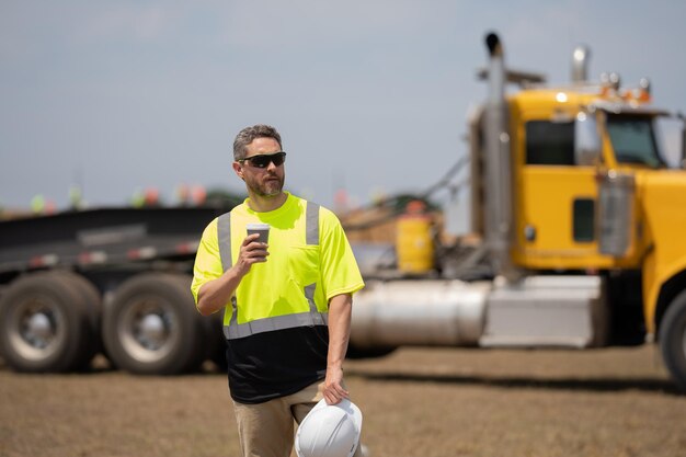 Trabalhador no empreiteiro de coffee-break observou o local do empreiteiro de construção com capacete e coletes de segurança no canteiro de obras empreiteiro no local de trabalho empreiteiro na construção