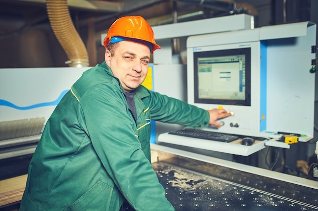 Trabalhador operando máquinas controladas por computador na fábrica